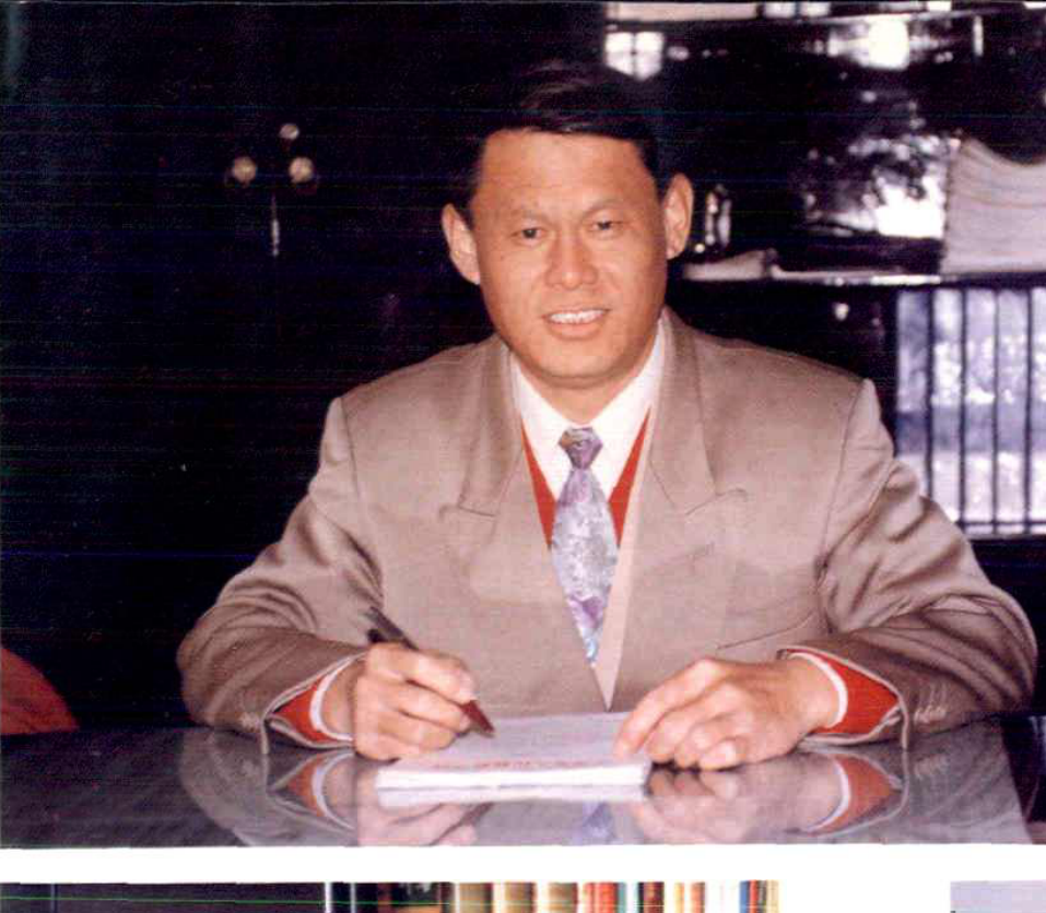 一名男子坐在桌前正在书写的半身照片