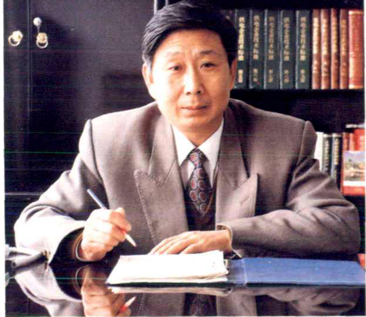 一名男子坐在书架前正在书写的半身照片