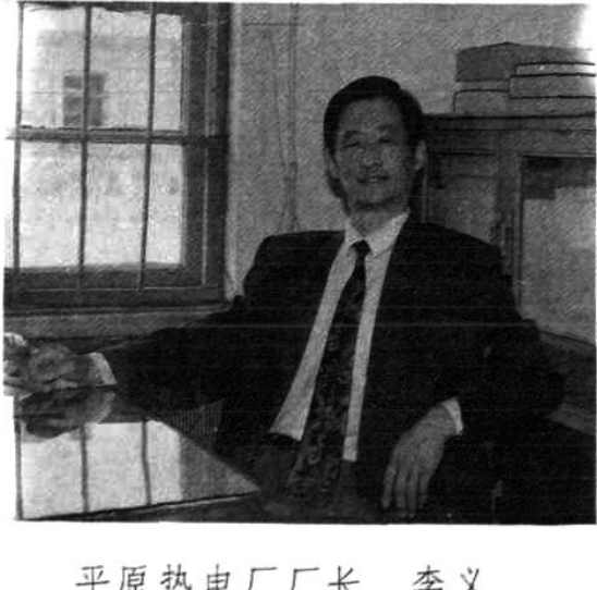 一张黑白照片，展示一名身穿西装的男子坐在桌前办公。