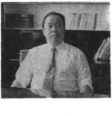 一张人物黑白照片，男子坐在办公室中