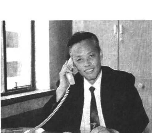 一张黑白照片，展示一名男子手持电话正在接听。