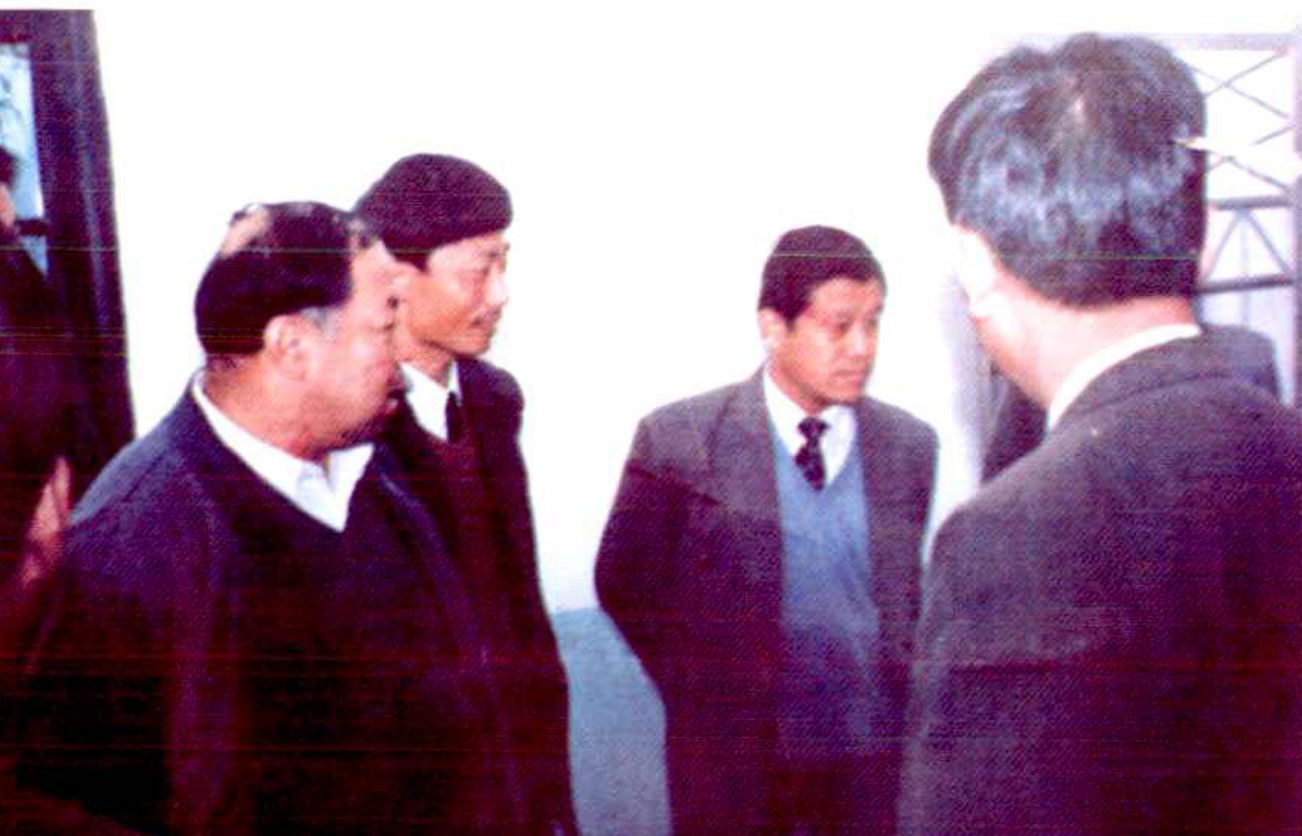 一群人在室内，其中两人正在交谈，另外两人站在一旁。