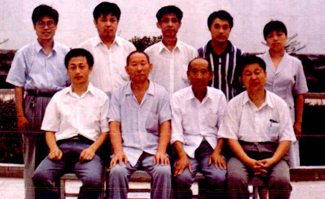 一行七人在室内合影，第一排三人坐着，第二排四人站着。