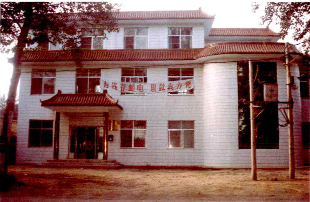 一座白色的两层楼建筑，有红色的屋顶，楼前有庭院