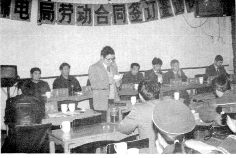 一群人在室内进行劳动合同签订仪式，有人在发言，有人在观看。