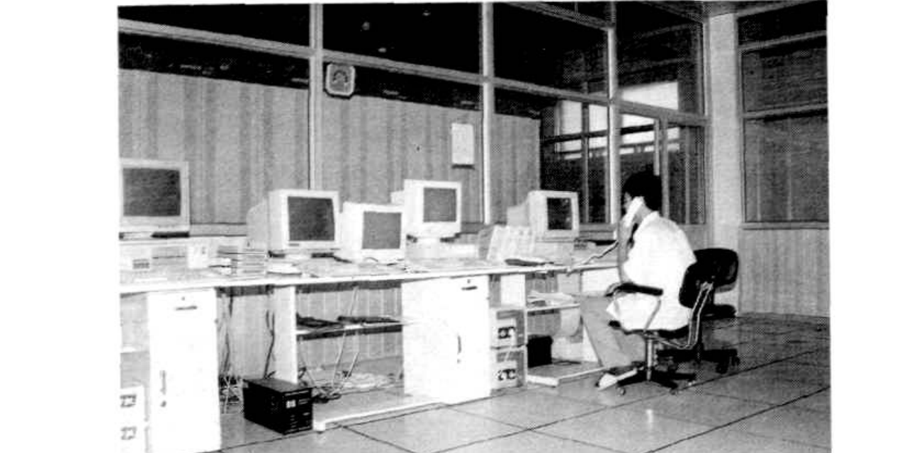 一排电脑主机和显示器，一人坐在椅子上操作其中一台电脑。