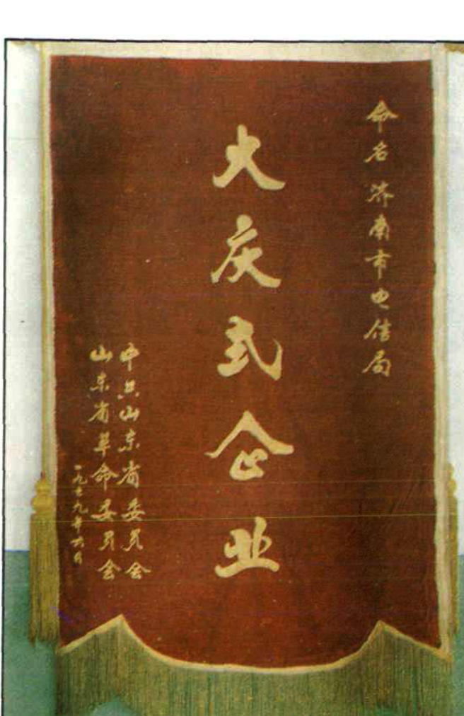 一面红底黄字的锦旗，上书“大庆式企业”及落款。