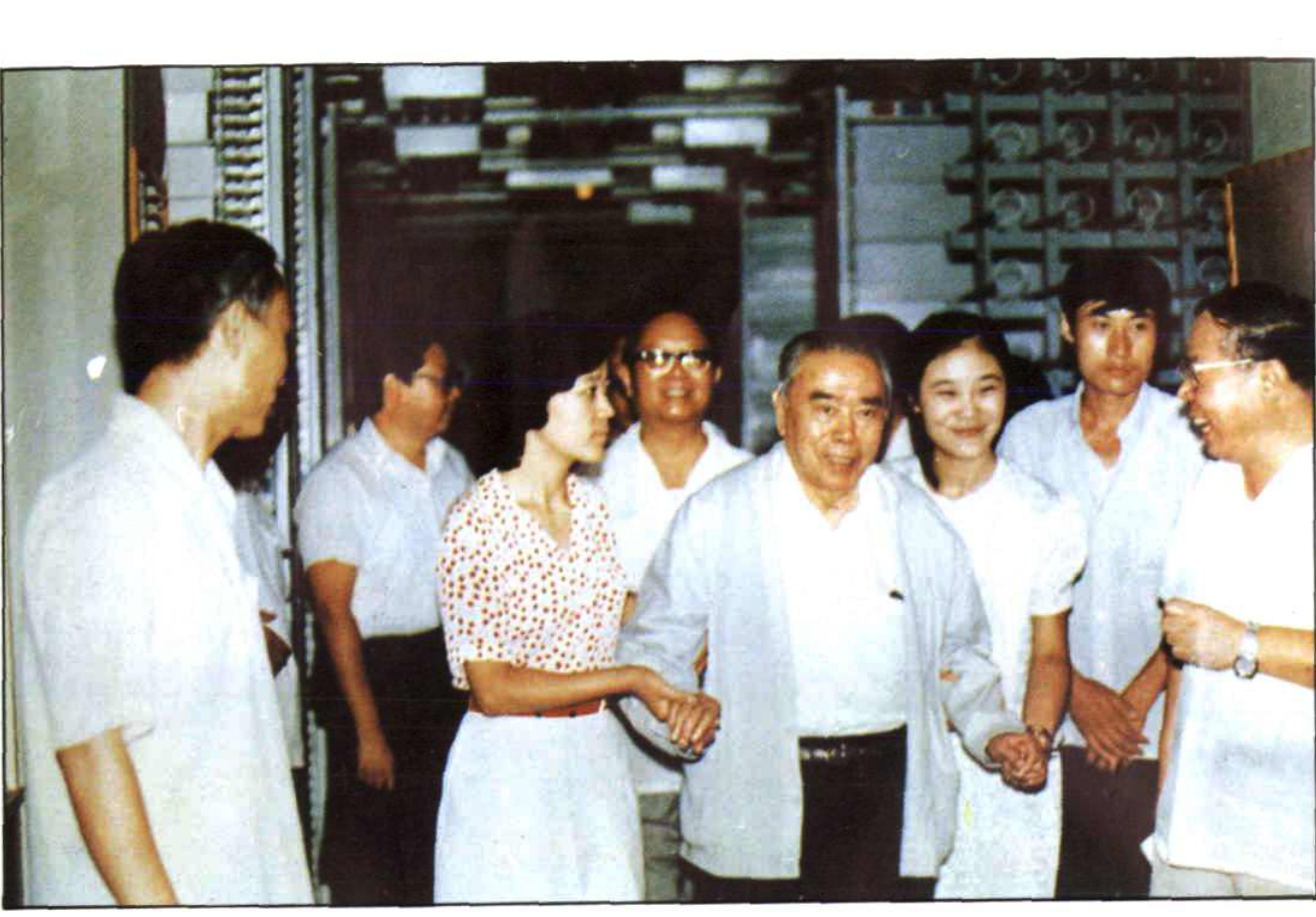 几位男女在室内合影，中间一位长者向前走动