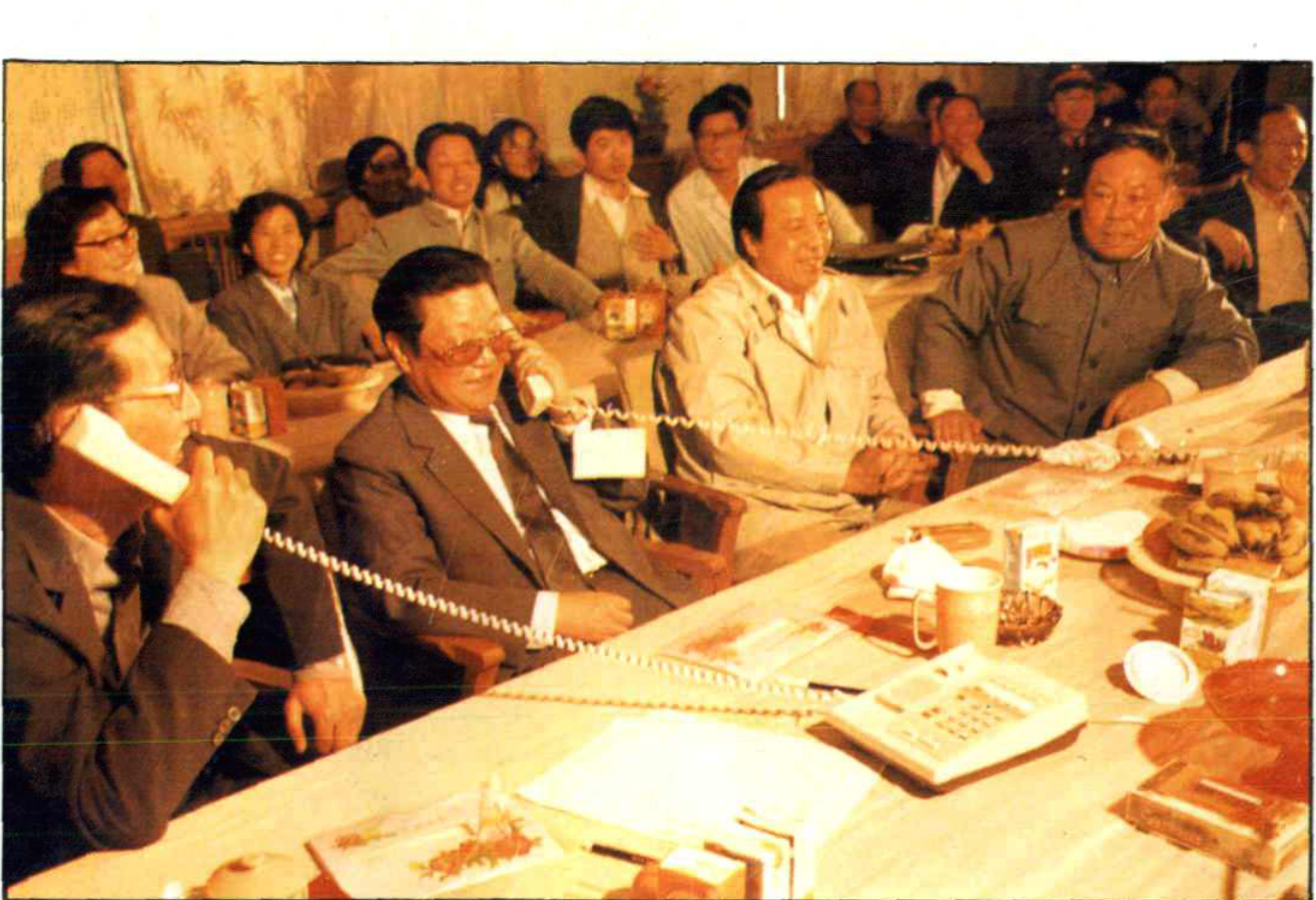 多位领导干部和群众在室内开会并使用电话