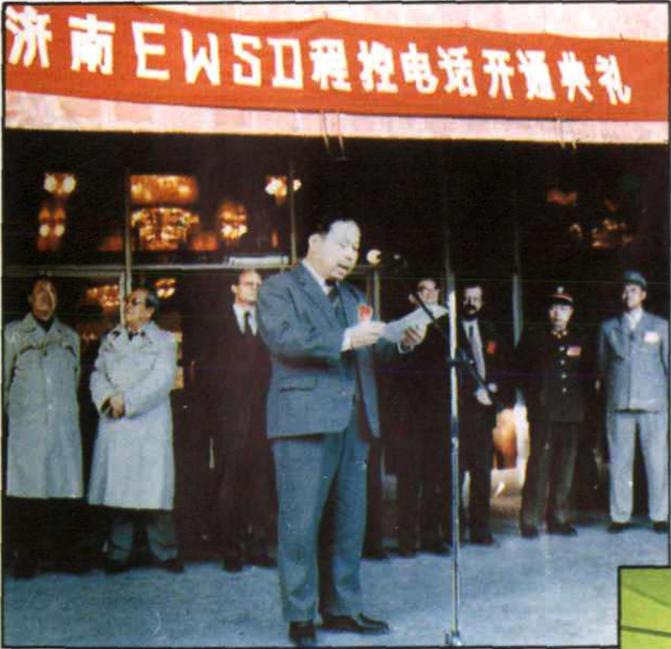 室外程控电话开通典礼现场，一人在发言，身后挂有横幅