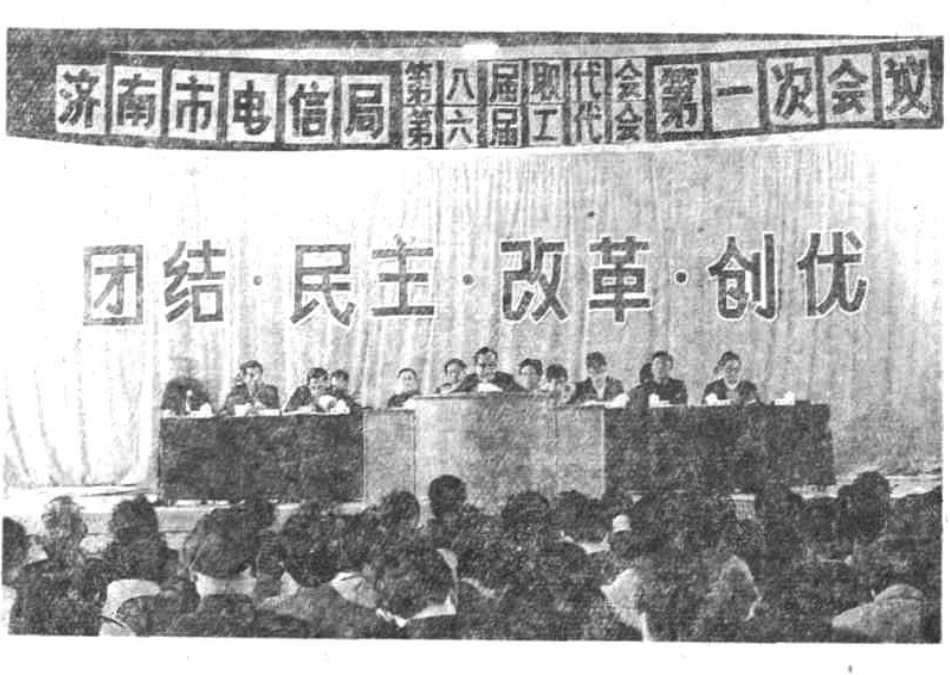 一张黑白会议照片，上方带有横幅文字，下方是主席台和台下与会人员