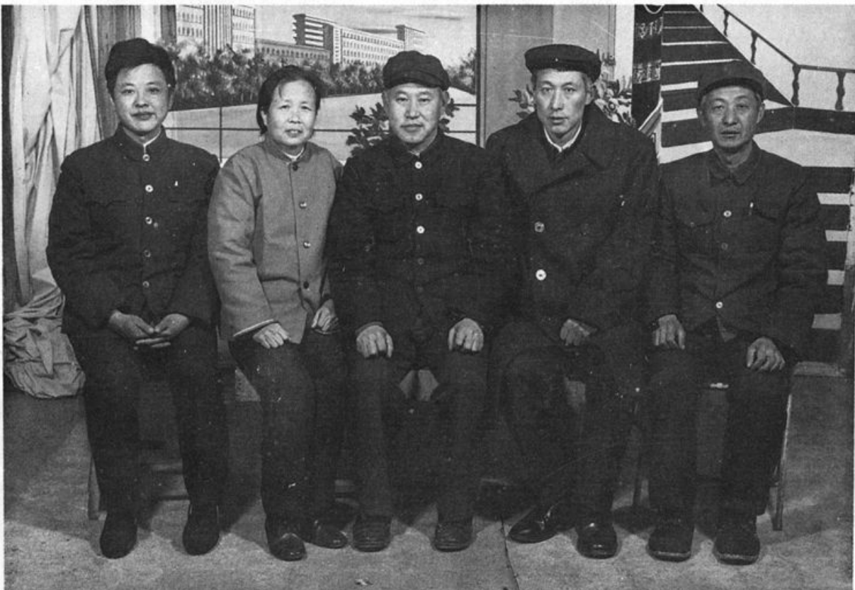 黑白合影照片，五位穿着中山装或传统中式服装的男女员工正襟危坐或端正合影。