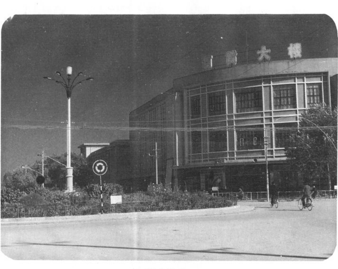 黑白照片，展示百货大楼外观街景与前的道路及路灯