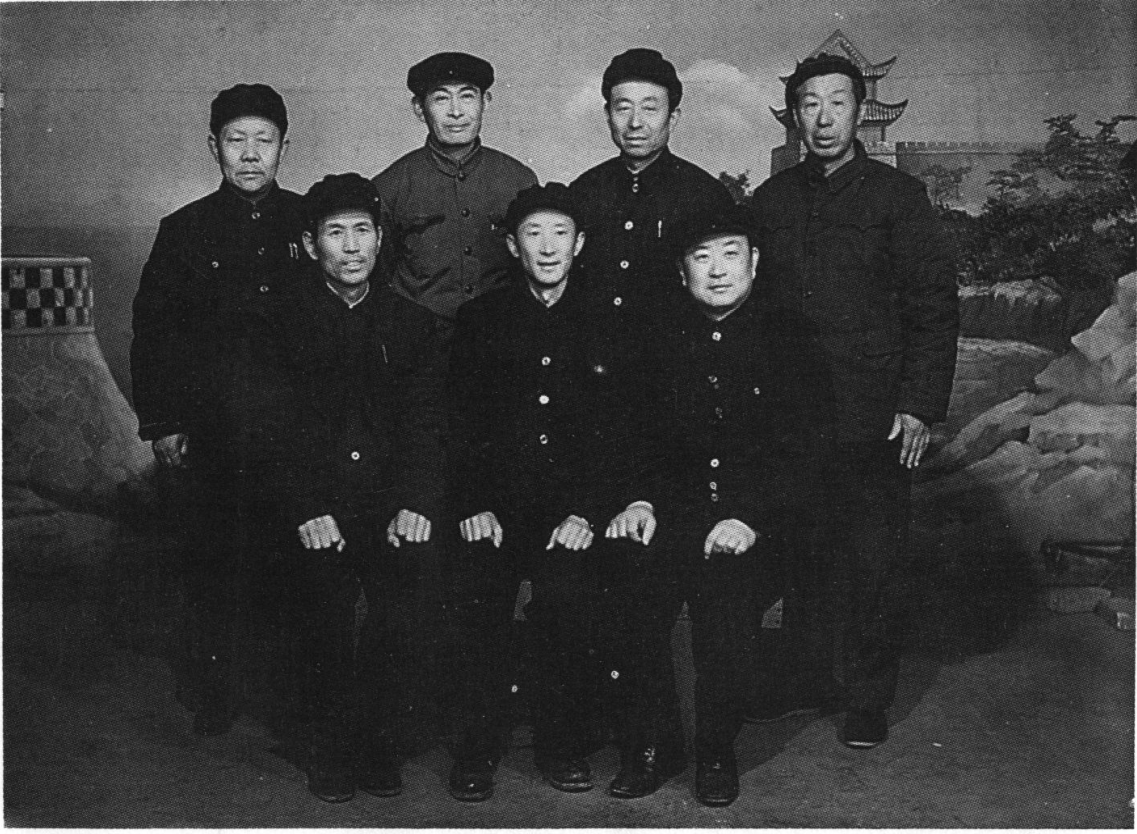 黑白合影照片，八位身着深色中山装的男子合影