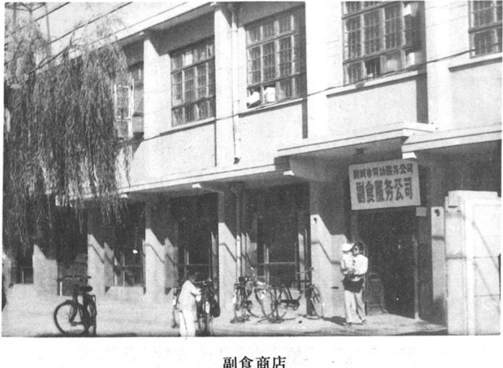 黑白老照片，拍摄了一家名为副食商店的两层建筑外观，门口停放着自行车，有人在门前走动。