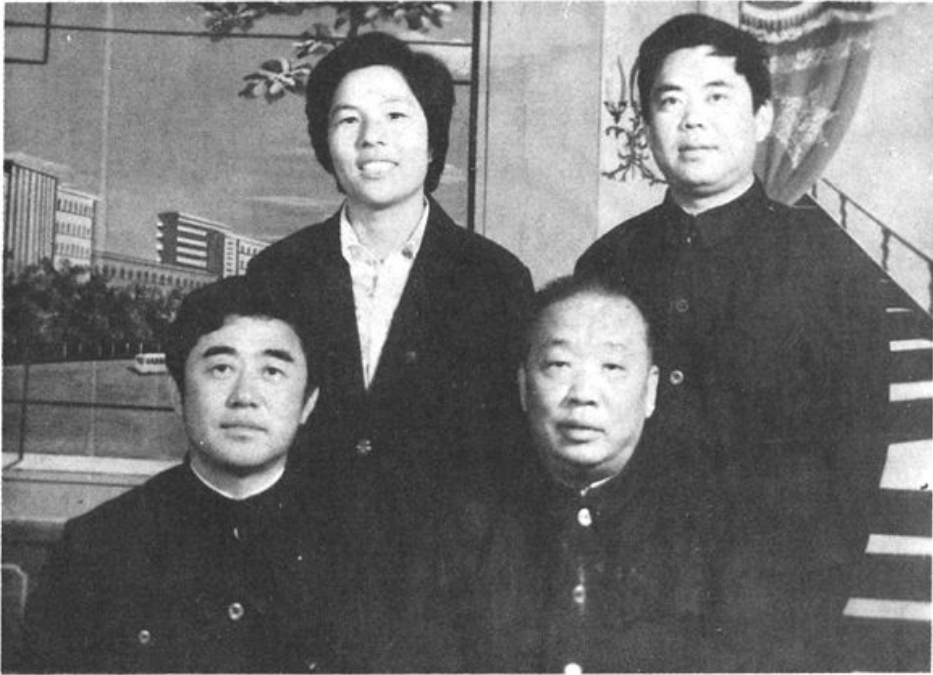 一张黑白合影照片，四位男女同志在室内背景前合影。