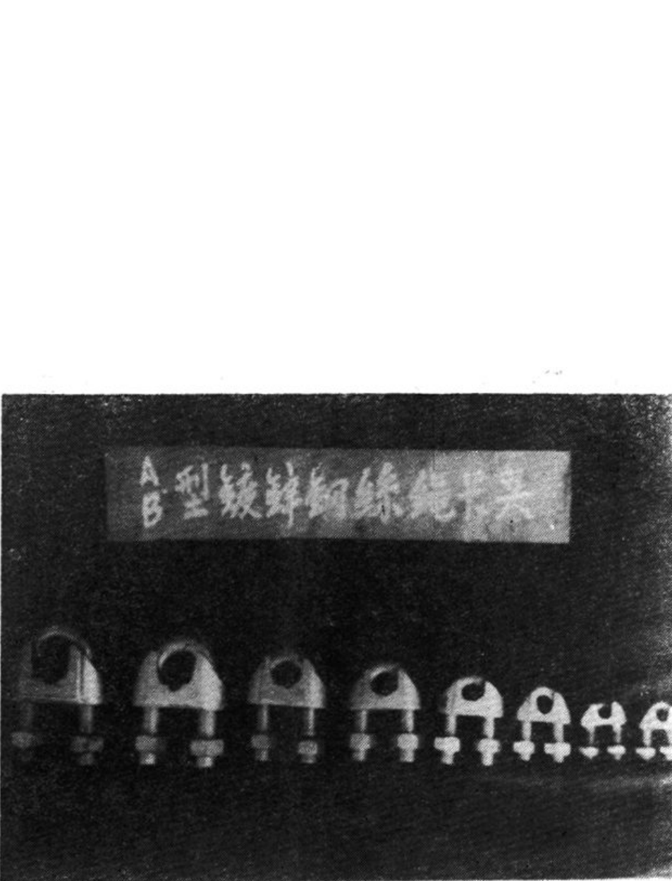 展示玛钢厂出口的钢丝绳卡头产品照片，包含带有文字标签的展板以及不同规格的卡头