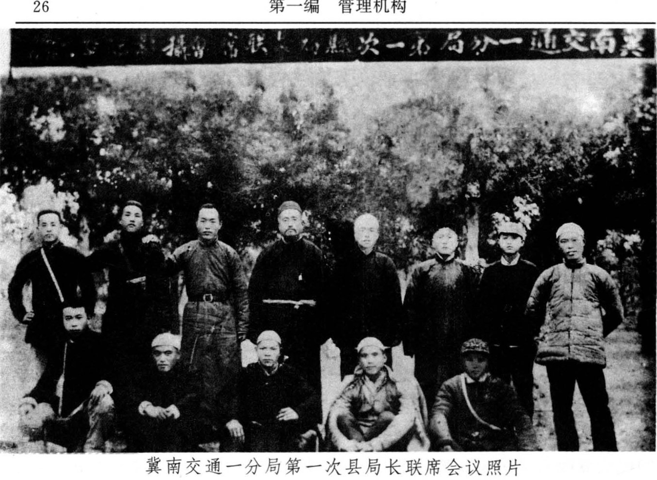 一张黑白合影照片，包含多名穿着朴素的男子站立和蹲坐。