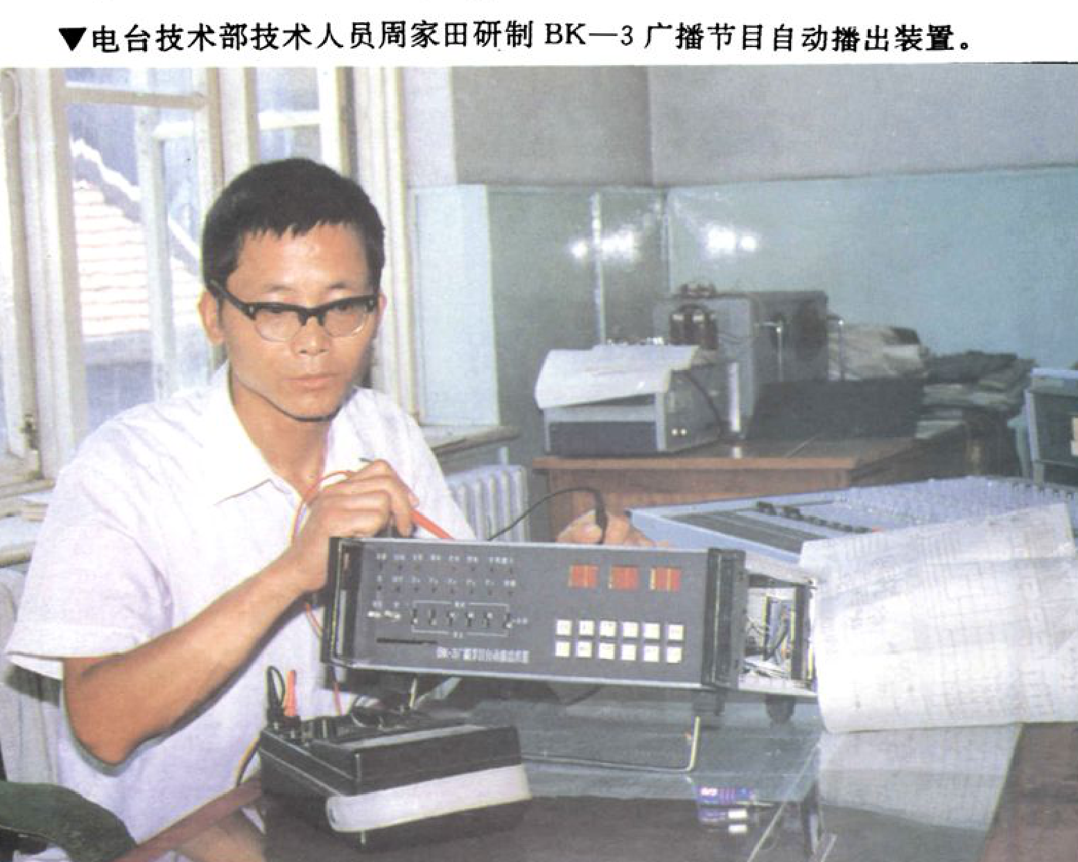 一名戴眼镜的男子正在操作一台带有按钮和显示屏的电子设备。