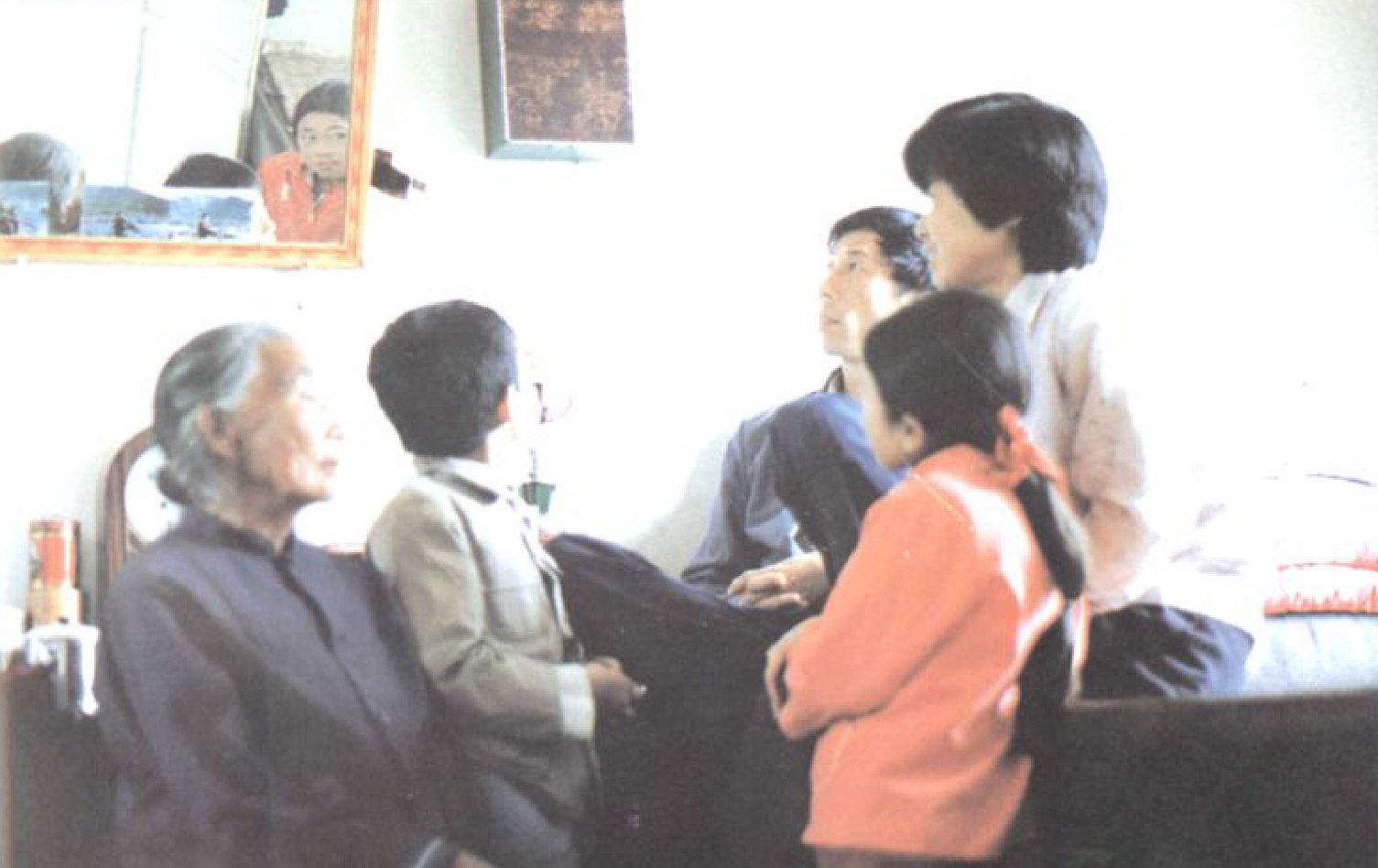 几位村民围坐在一起，其中有老人、儿童和中年人，似乎在收听广播。