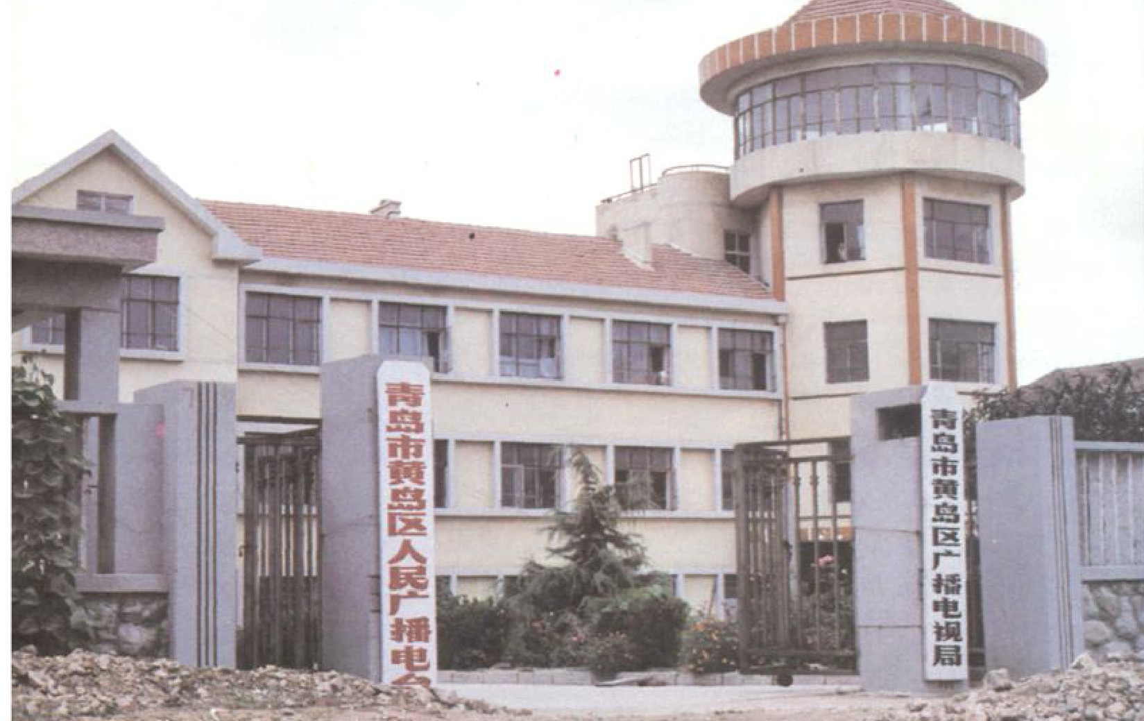 一栋办公楼和一座带圆型塔楼的建筑，楼前有牌示。