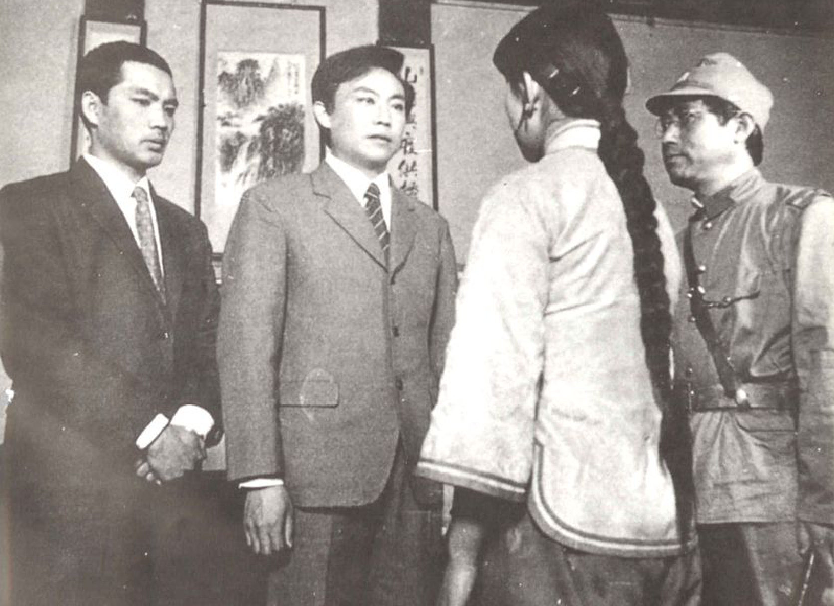 四个人物在室内合影，其中两人穿着西装，一人穿着长辫子，另一人穿着军装。
