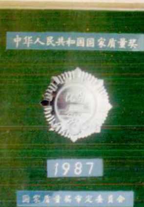 一个圆形徽章，上面有“1987”字样和奖章的图案。