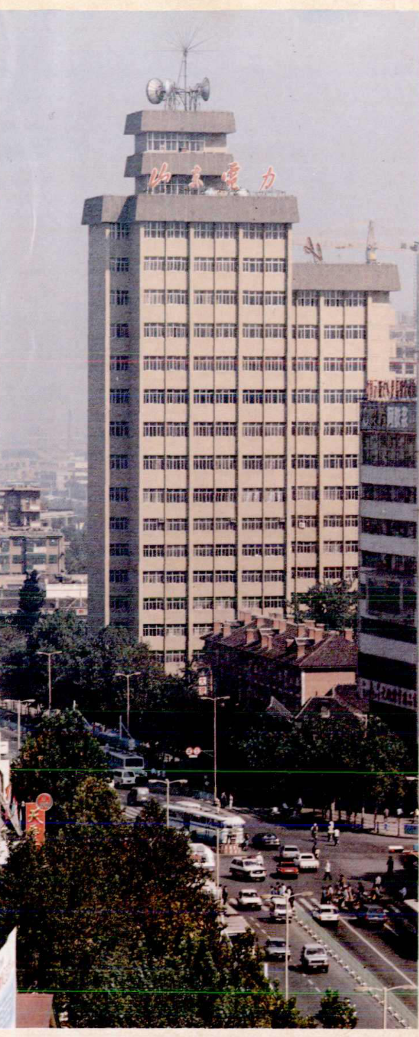 一栋高大的建筑，顶部有天线和标志，楼下是街道和车辆。
