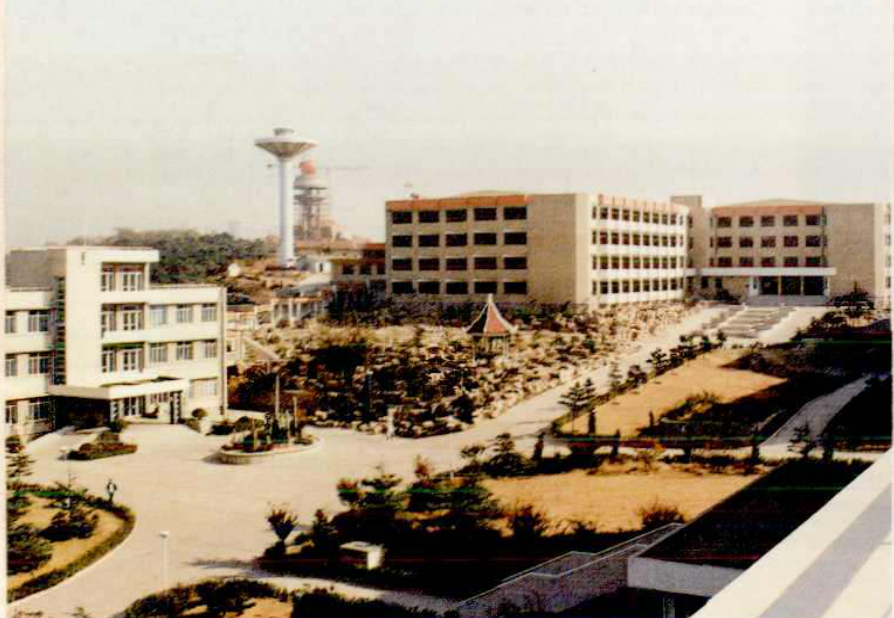 一栋多层建筑群，有水塔，院内有树木草地