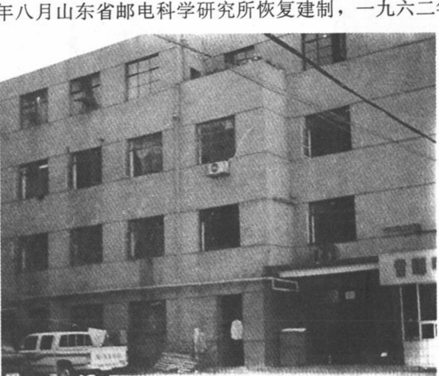 黑白历史照片，展示一栋多层建筑外观及门前停放的汽车。