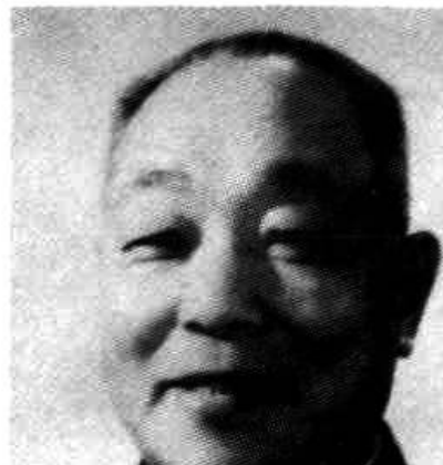 一位身着中山装的男士面带微笑，拍摄角度为正面，背景为浅色。