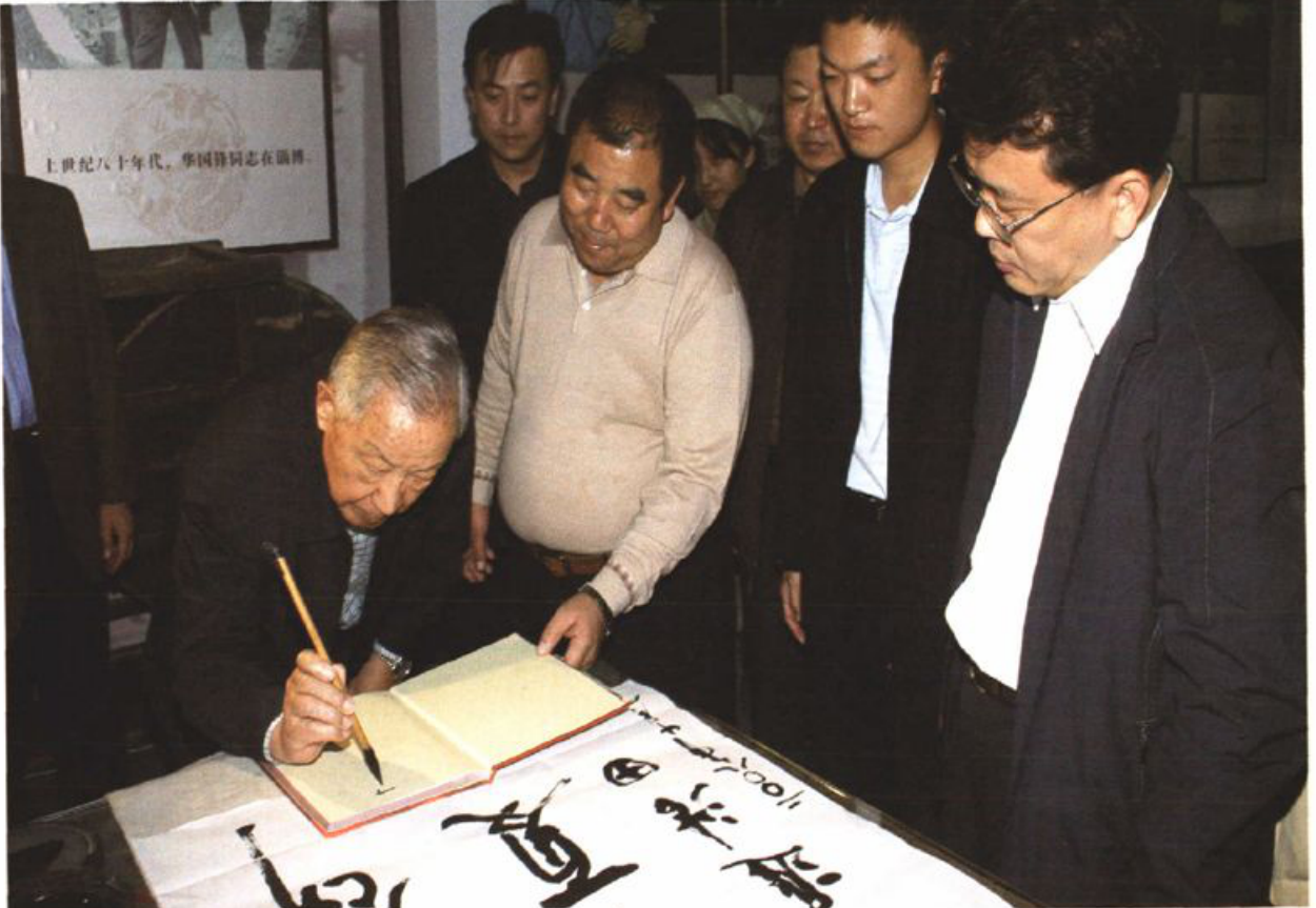 一张历史照片，显示多人围观一人题字。