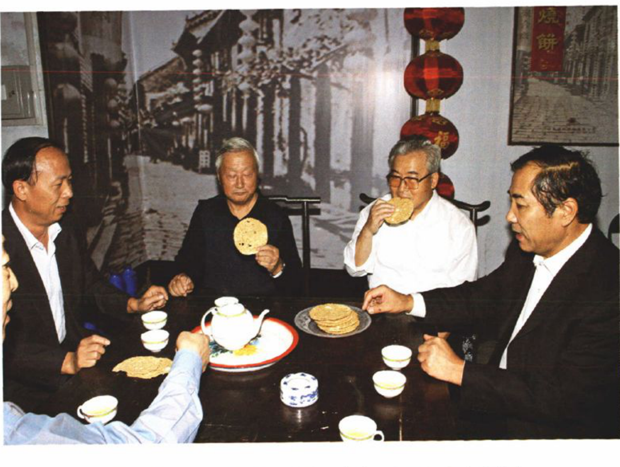 一张历史照片，显示几人围坐在桌旁用餐。