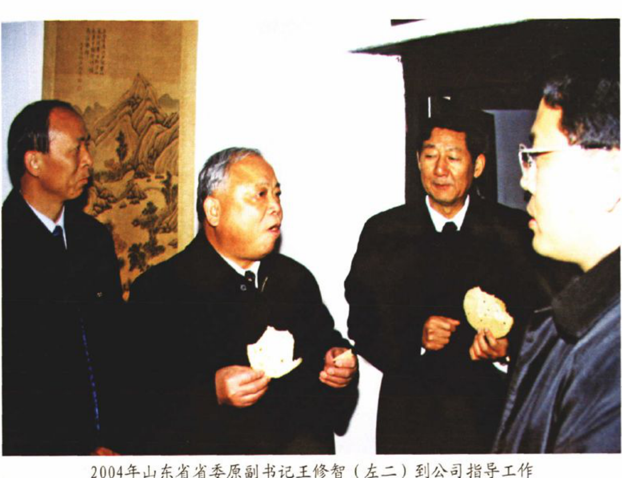 四名男子在室内交谈，其中一人手中拿着白色物品。