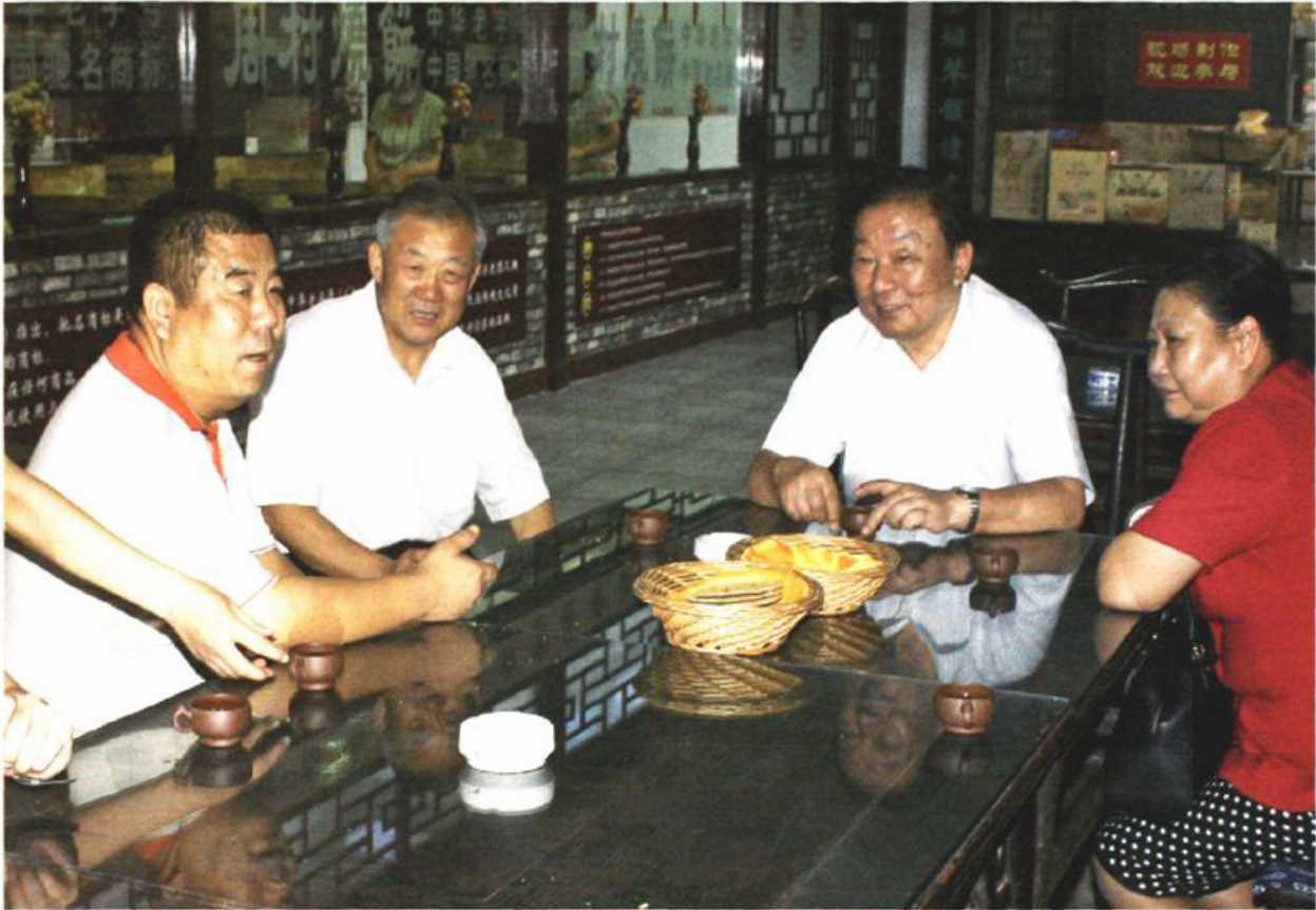 四人围坐在玻璃桌旁交谈的照片