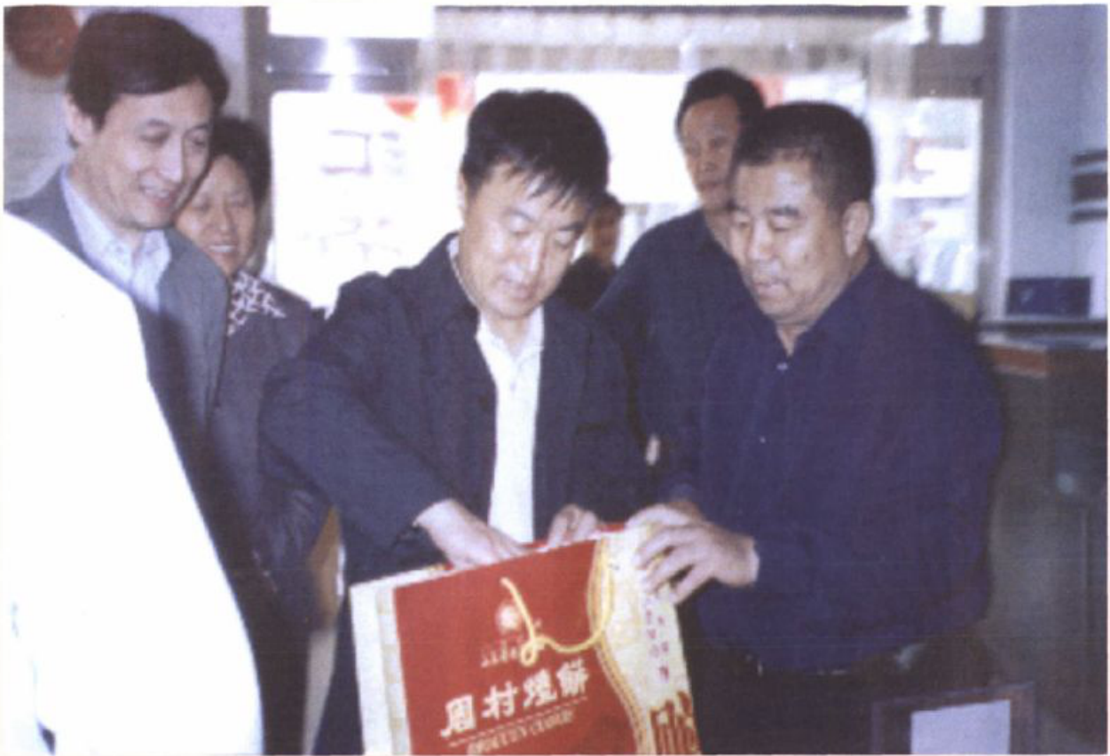几名男子在室内查看带有周村烧饼字样的红色手提袋