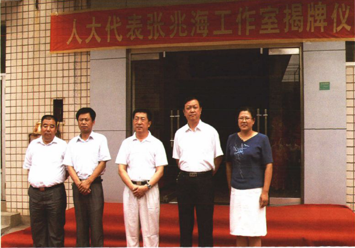 五人站在写有“人大代表张兆海工作室揭牌仪式”横幅的建筑门口合影。