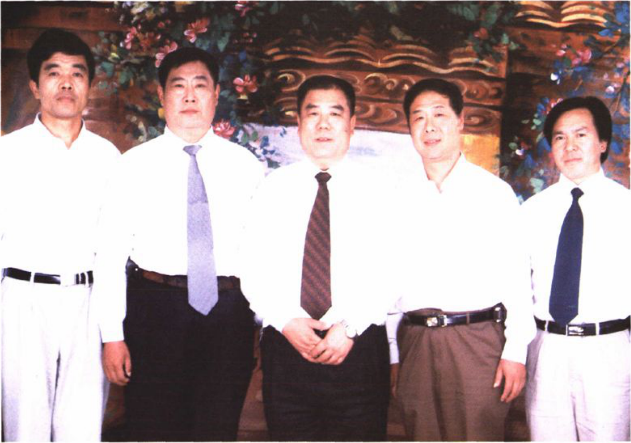 五名身穿白色衬衫和西裤的男子并排站立的合影