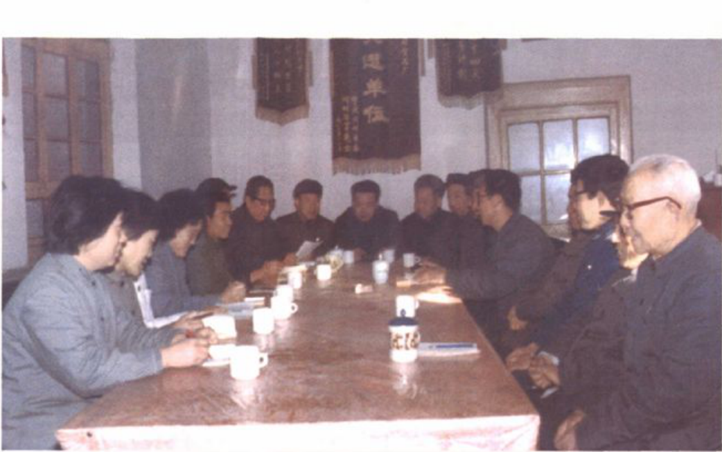 多人围坐在长桌旁开会的黑白照片