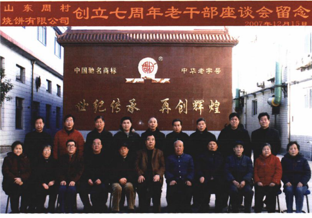 山东周村烧饼有限公司创立七周年老干部座谈会合影，合影人员在一处建筑物前合影