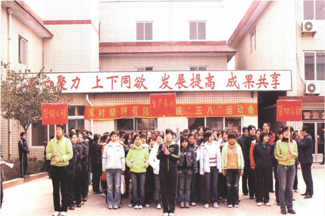 多人站在建筑前合影，拉有横幅