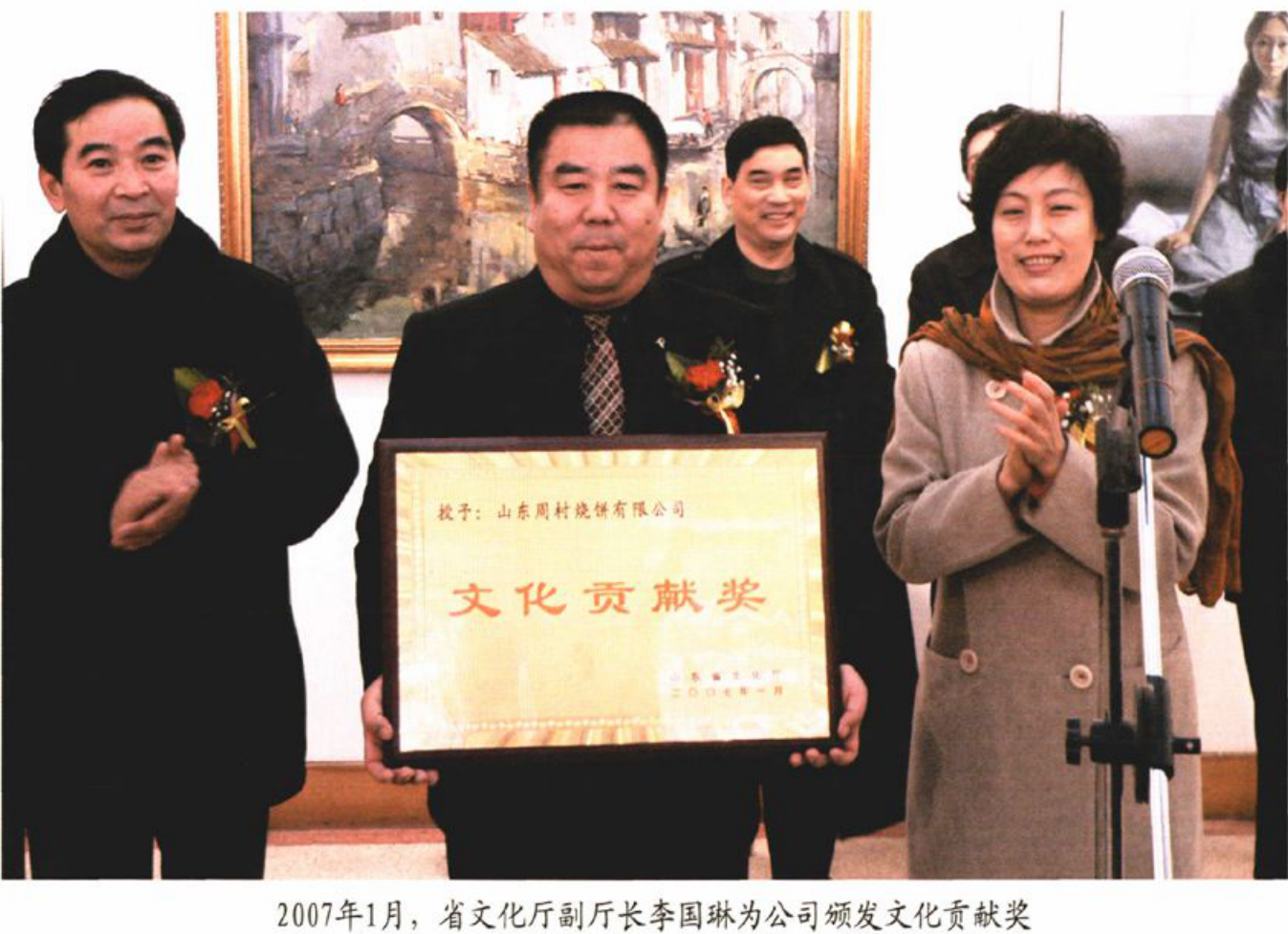 几人手持写有“文化贡献奖”的奖牌在室内合影