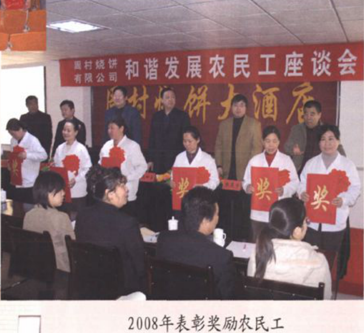 一张室内合影照片，背景有“和谐发展农民工座谈会”字样横幅，多人在会议桌前举着荣誉证书