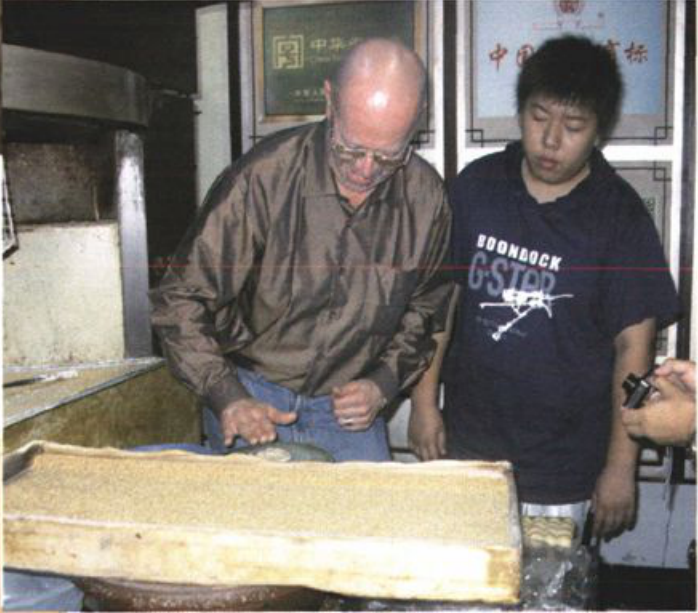 一名外国男子与另一名年轻男子在操作台前制作烧饼的场景