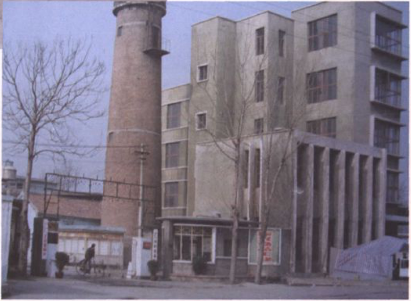 一张展示带有烟囱和多层建筑的厂区一角的彩色照片