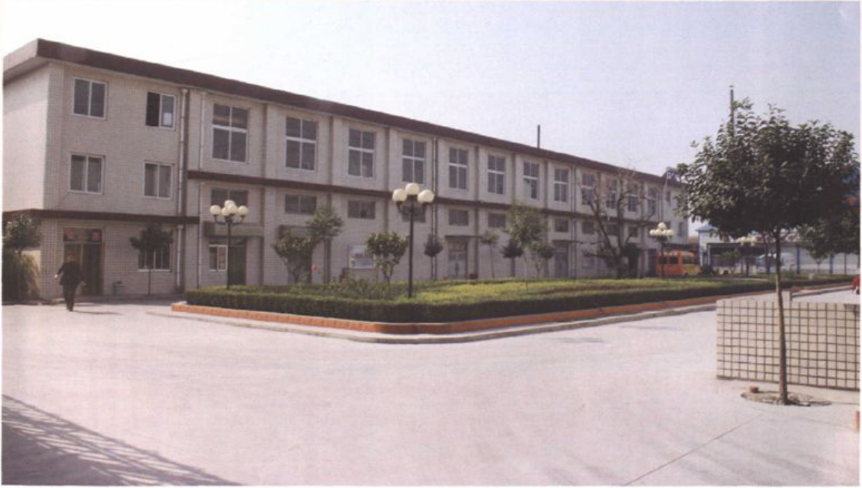 一张展示现代化多层厂房与前庭绿化的彩色照片