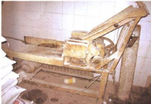 黑白照片显示建厂初期使用的木质和金属结构的压面机设备。