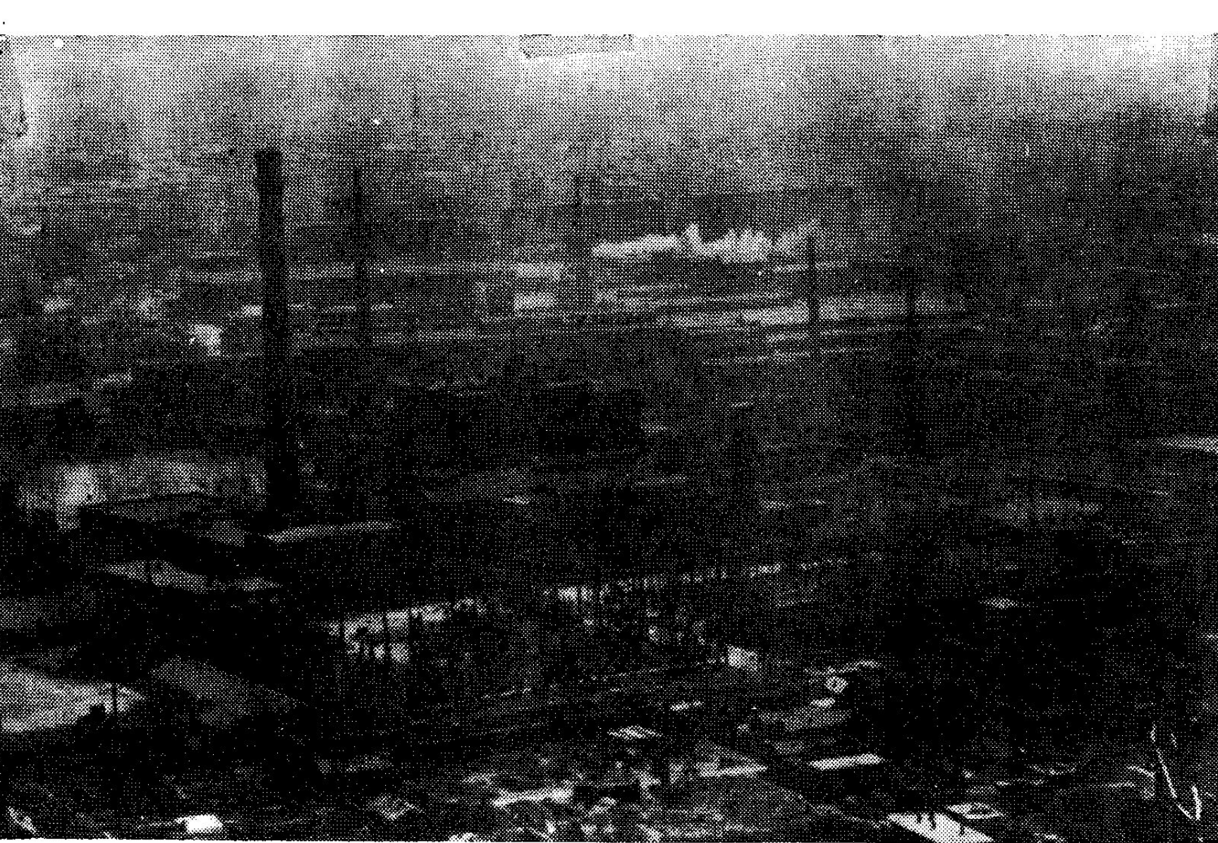 黑白历史照片，展示博山火力发电厂及其周边的厂区建筑和高耸烟囱景观